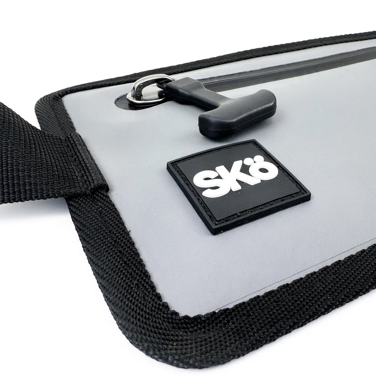 Phone Pouch in Stone Gray, detail of the zipper pull, SKÖ logo patch and stitched fabric edging.