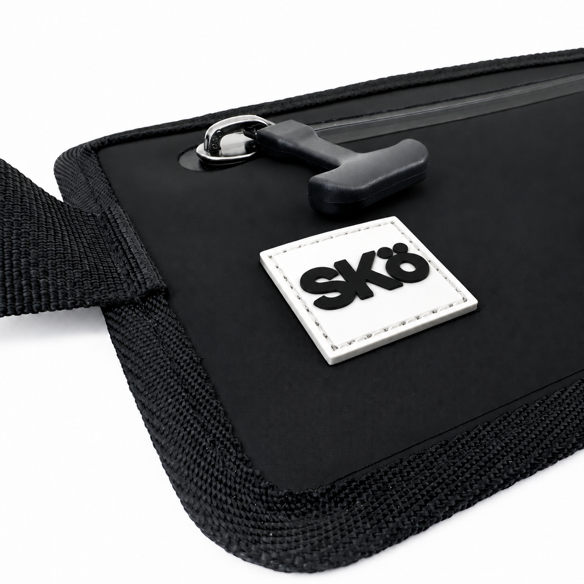 Phone Pouch in Matte Black, detail of the sealed zipper pull, stitched black edging and white square SKÖ logo.